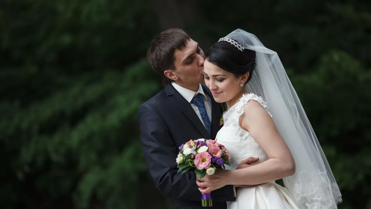 Jeune couple slave le jour de leur mariage, la mariée tenant un bouquet