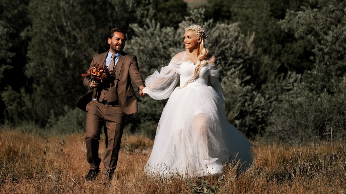 Jeune couple en mariage franco-russe marchant dans un champ, mariée en robe blanche, scène lumineuse en extérieur