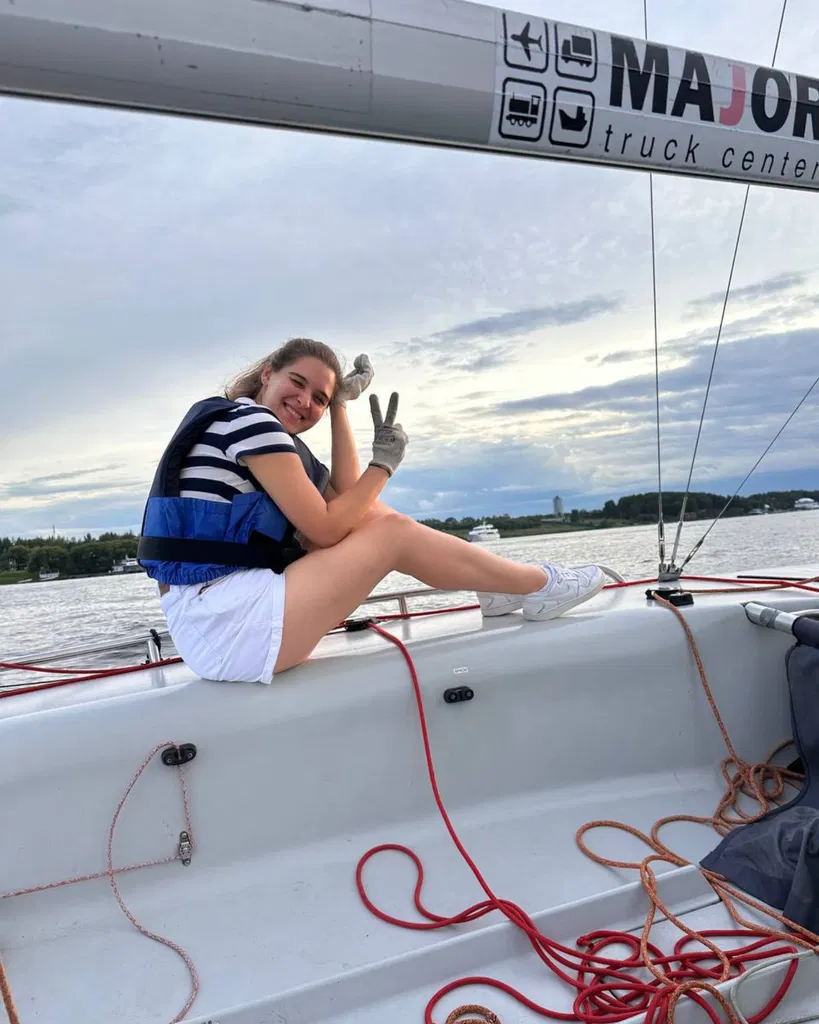 Olga en tenue de sport sur un yacht, avec l’eau en arrière-plan