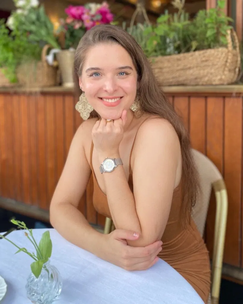 Photo d’Olga en gros plan dans un café, assise à une table, avec un sourire sur le visage